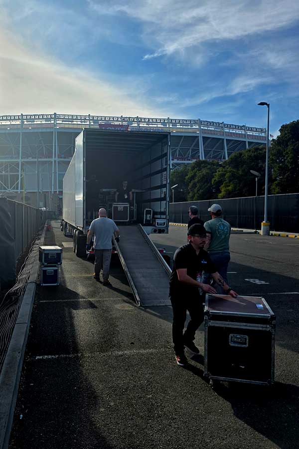 Facilitator and crew unloading gear at a stadium. 