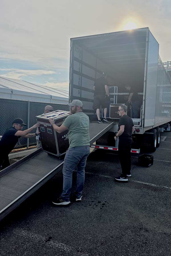 Facilitator and crew unloading gear at a stadium. 