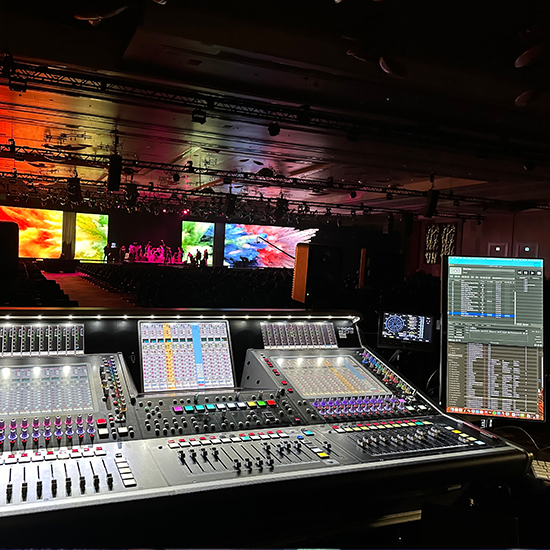 Audio control board facing a colorful stage